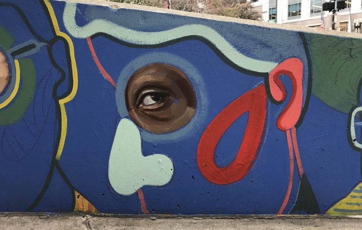 A mural of a portrait of a person drawn graphically with bright colors and a photorealistic eye