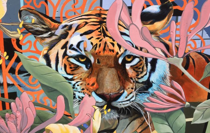A photorealistic painting of a tiger is surrounded by faded pink and yellow flowers. In the background, an organic orange line pattern surrounds the head of the tiger.